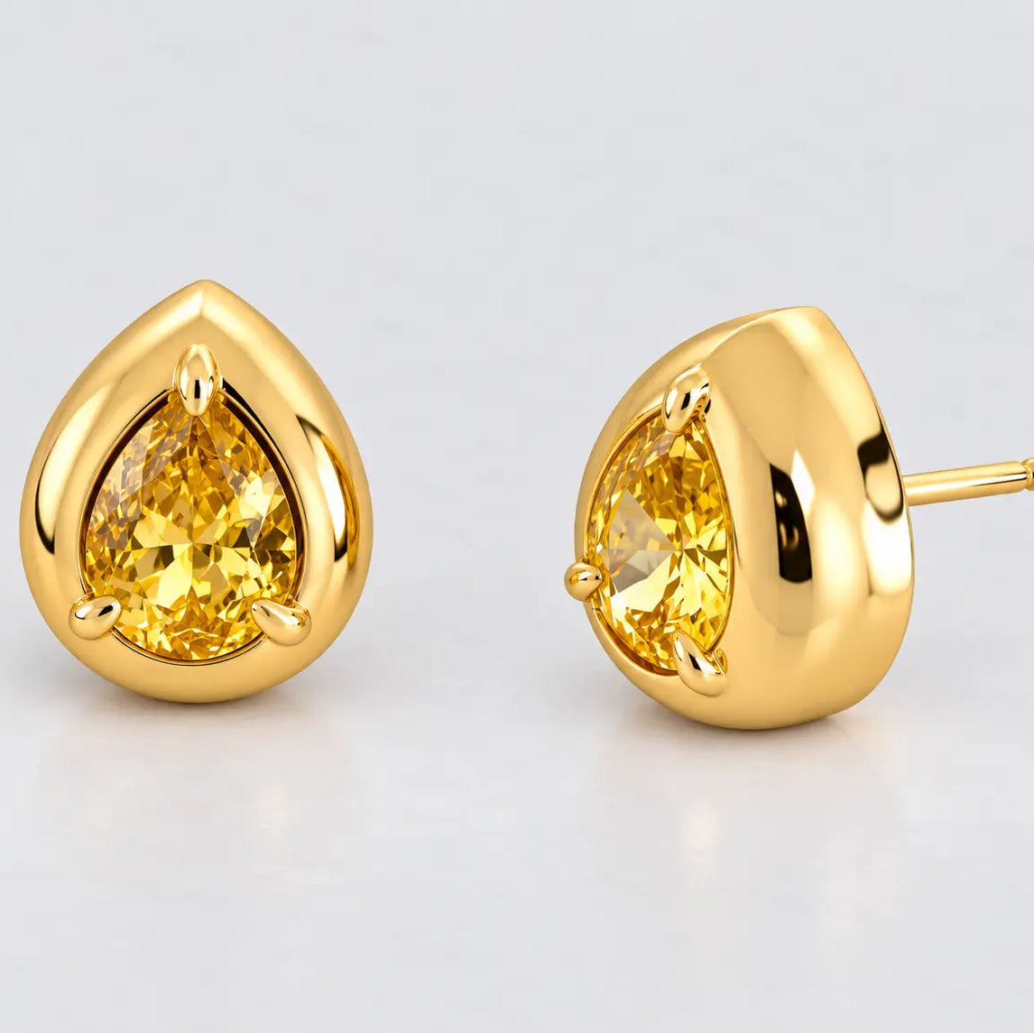 A pair of gold teardrop stud earrings with pear-cut yellow gemstones, shown on a clean light gray background. One earring is facing forward, and the other is turned to show the post and back.