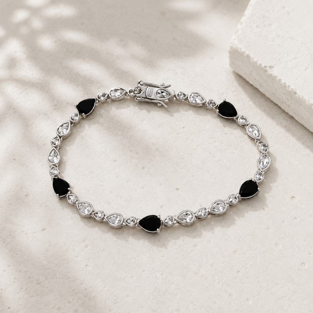 Silver bracelet with black and clear gemstones on a light surface