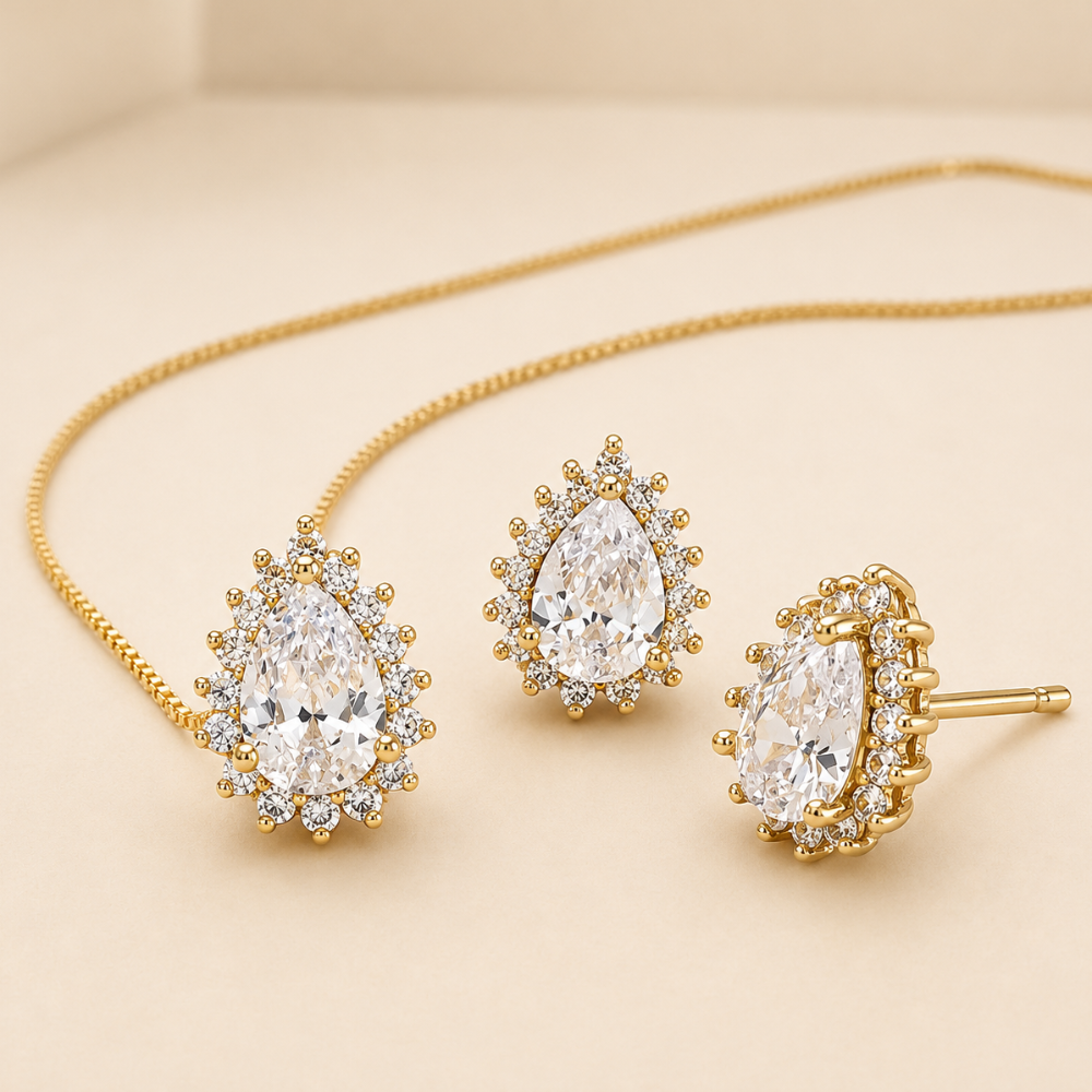 Gold necklace and earrings with clear gemstones on a beige background