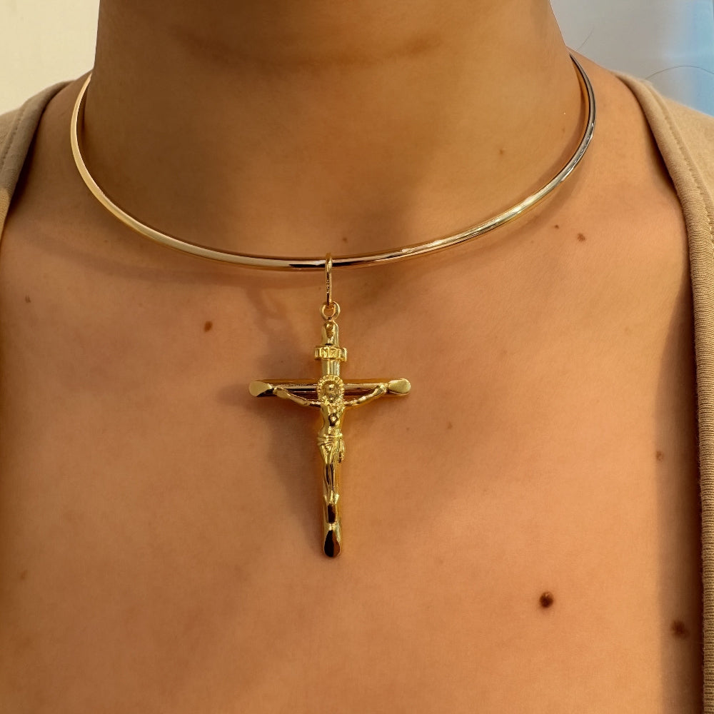 Gold necklace with a cross pendant worn by a person.