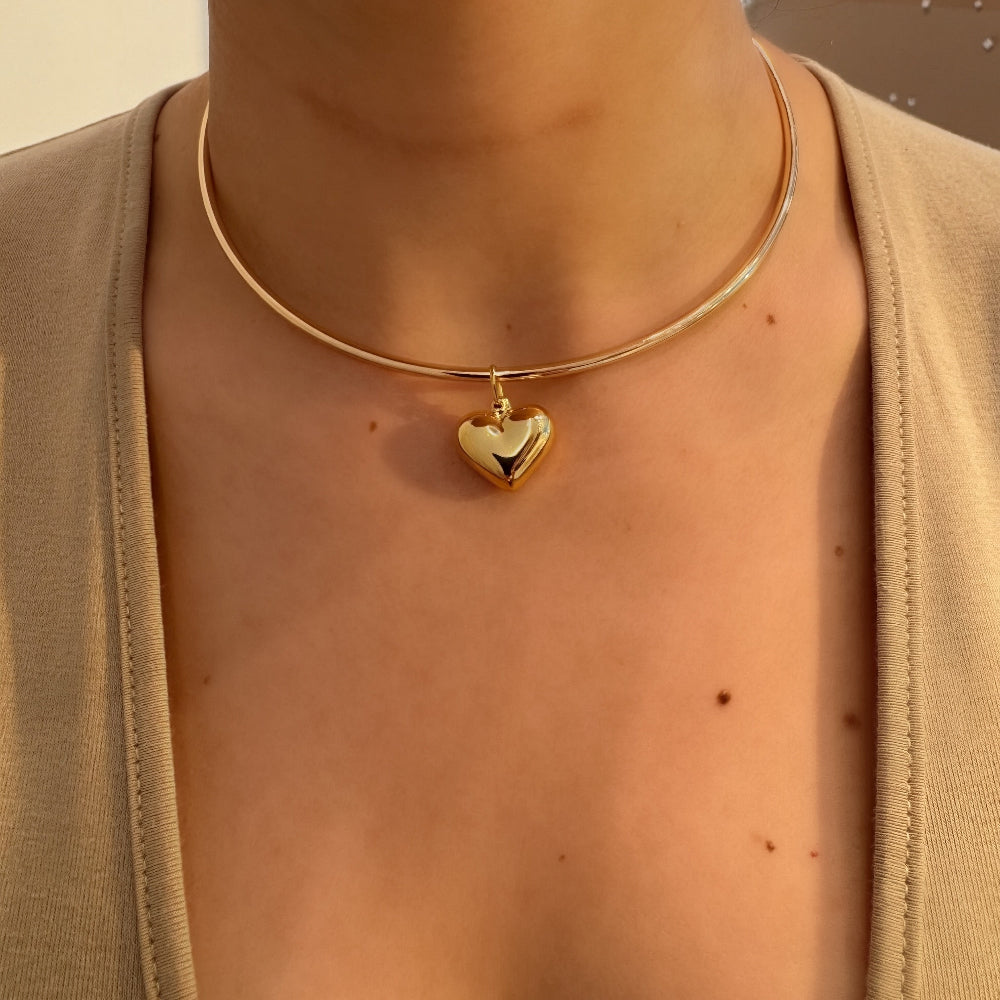 Gold necklace with a heart pendant worn by a person