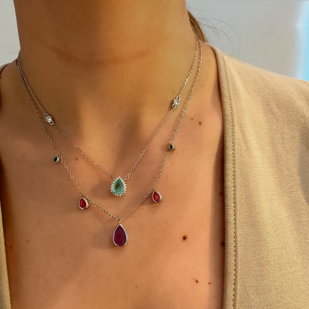 Necklace with gemstone pendants worn by a person, with a blurred background.