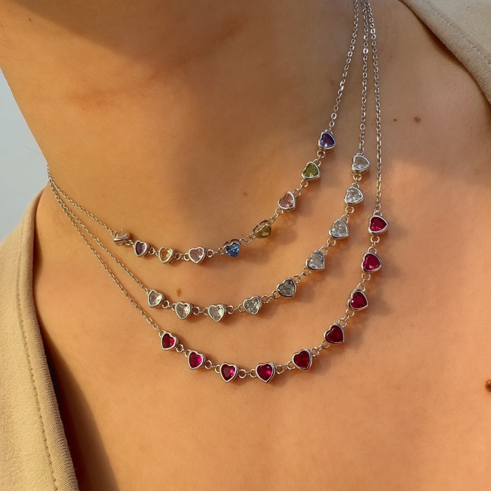 Necklace with heart-shaped gemstones on a person wearing a beige garment.
