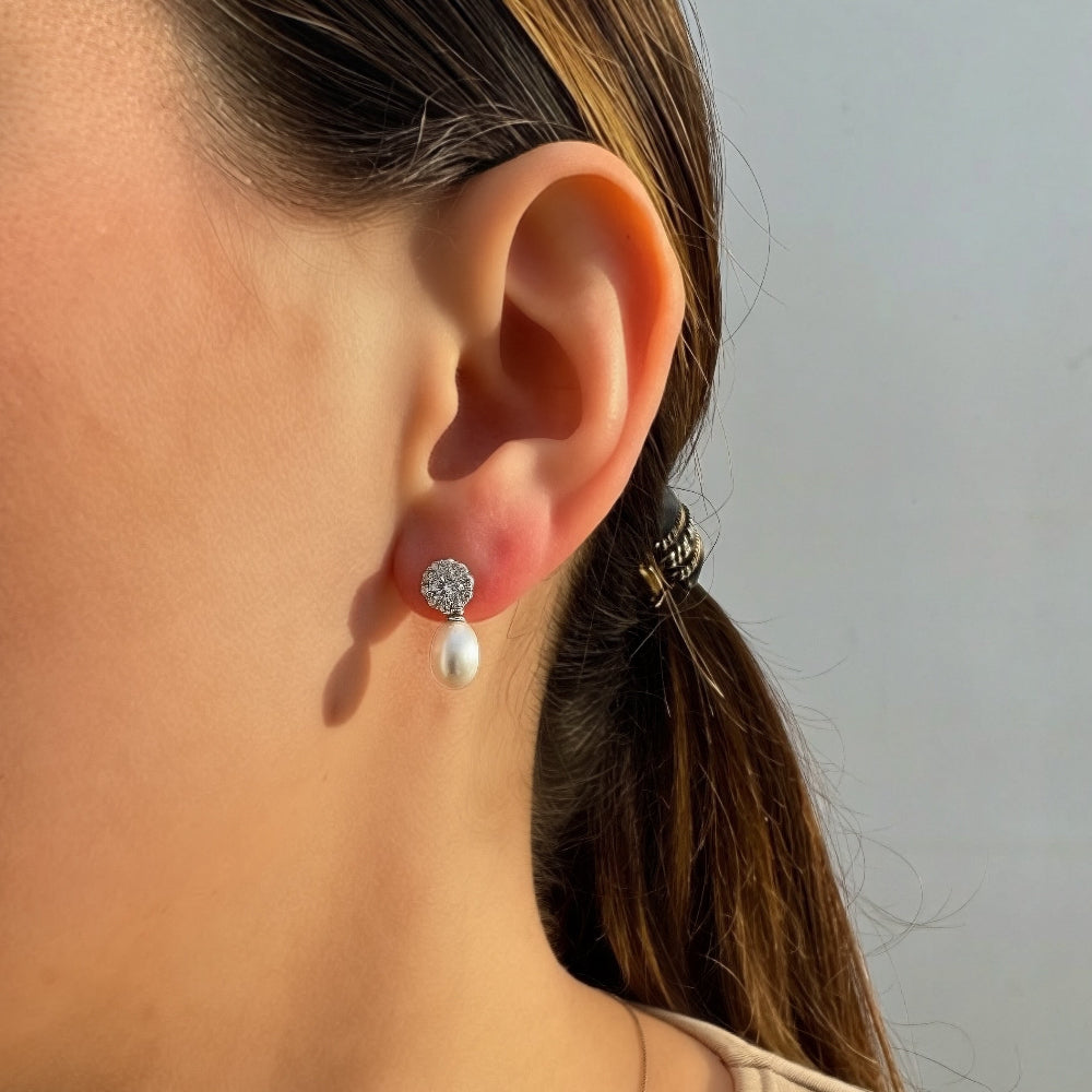 Close-up of a person wearing a pearl earring with a plain background