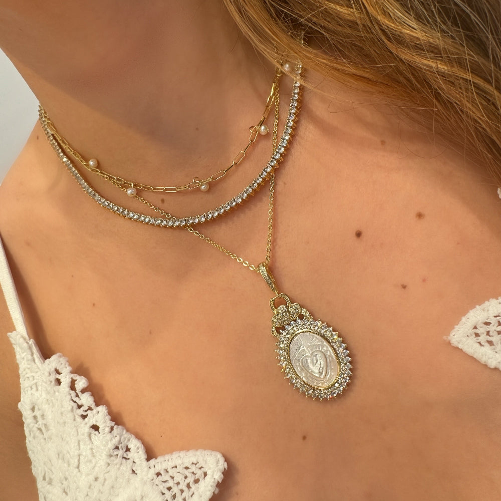 Close-up of a person wearing multiple necklaces with a focus on a gold pendant.