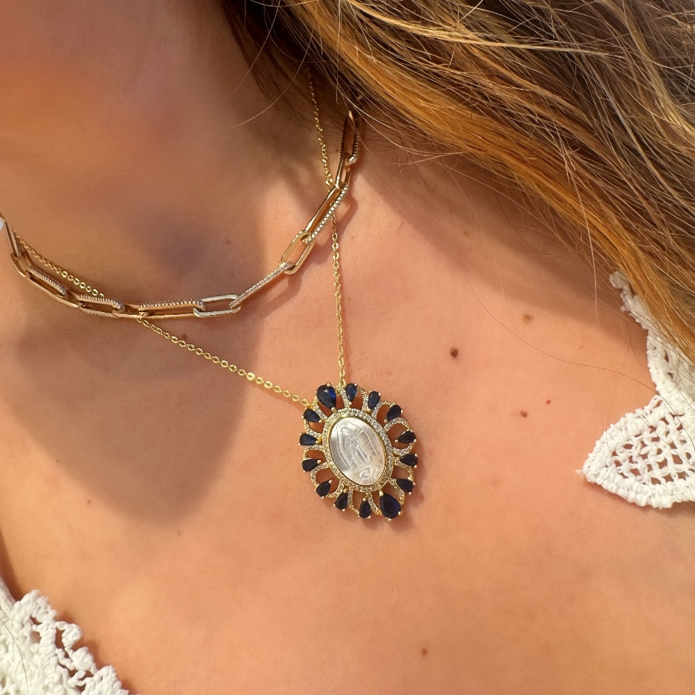 Close-up of a woman wearing a gold necklace with a decorative pendant.