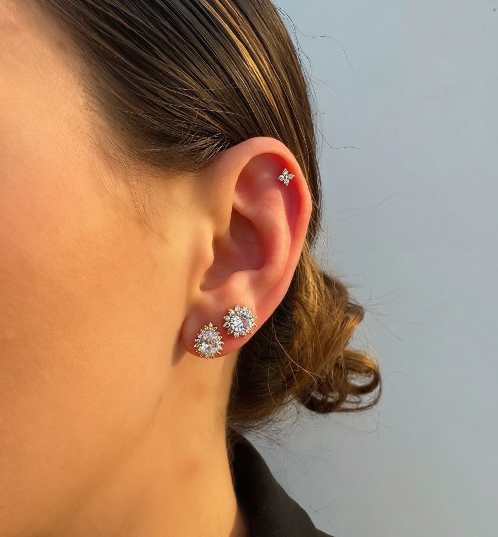 Close-up of a person wearing silver floral earrings against a neutral background