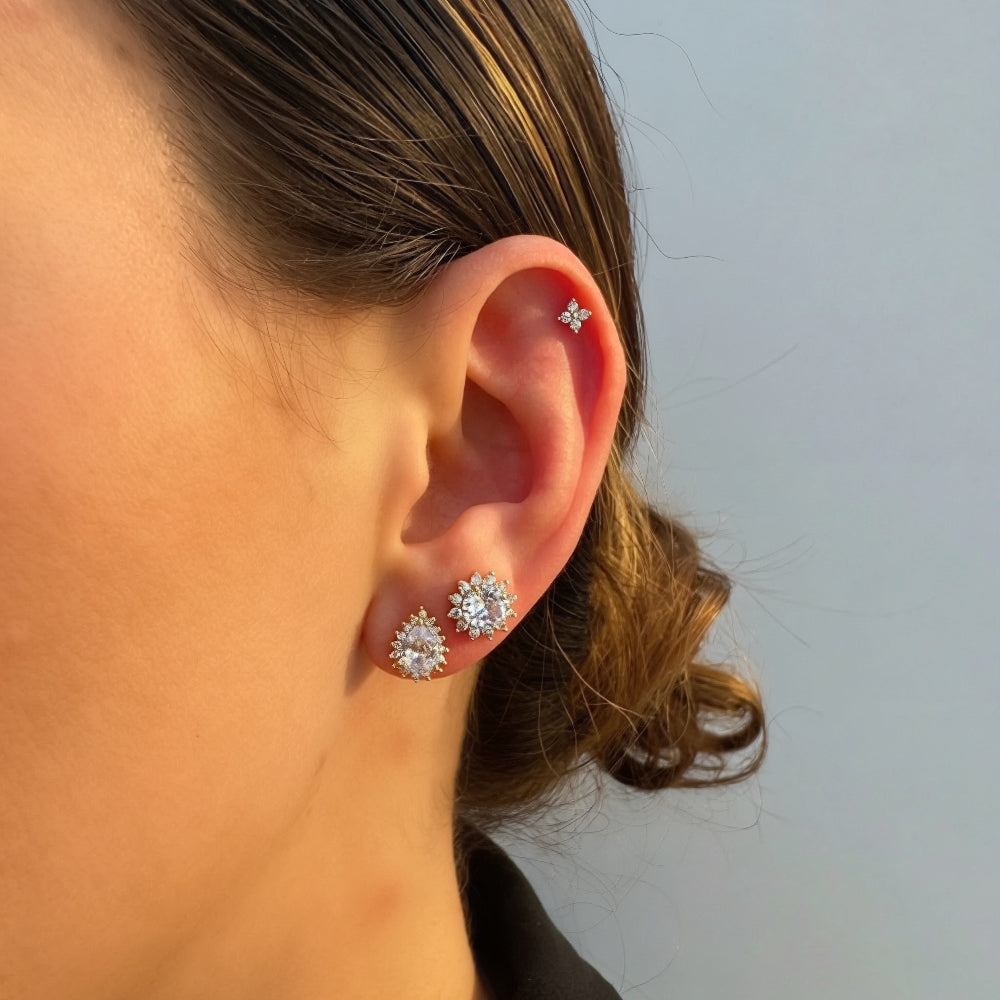 Close-up of a person wearing silver floral earrings against a neutral background