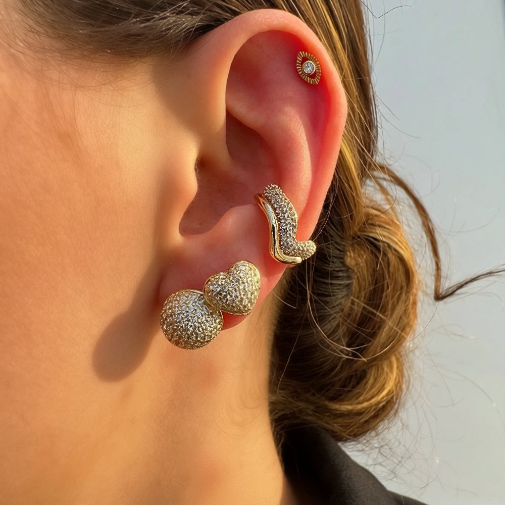Woman wearing pavé cubic zirconia heart stud earrings in a styled ear stack