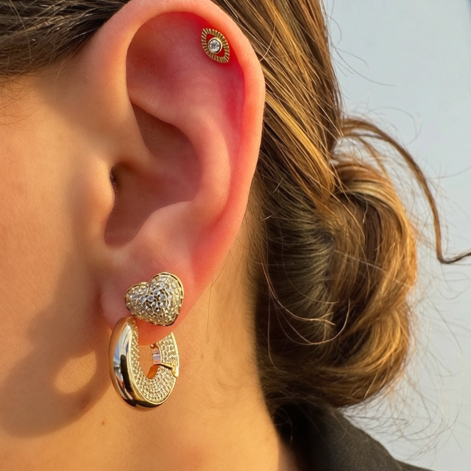 Close-up of an ear wearing gold hoop earrings with a blurred background