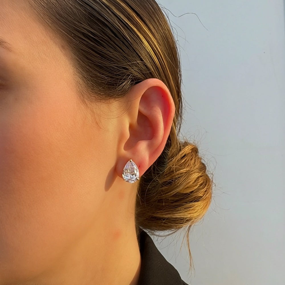 Close-up of a person wearing a pear-shaped diamond earring against a light background