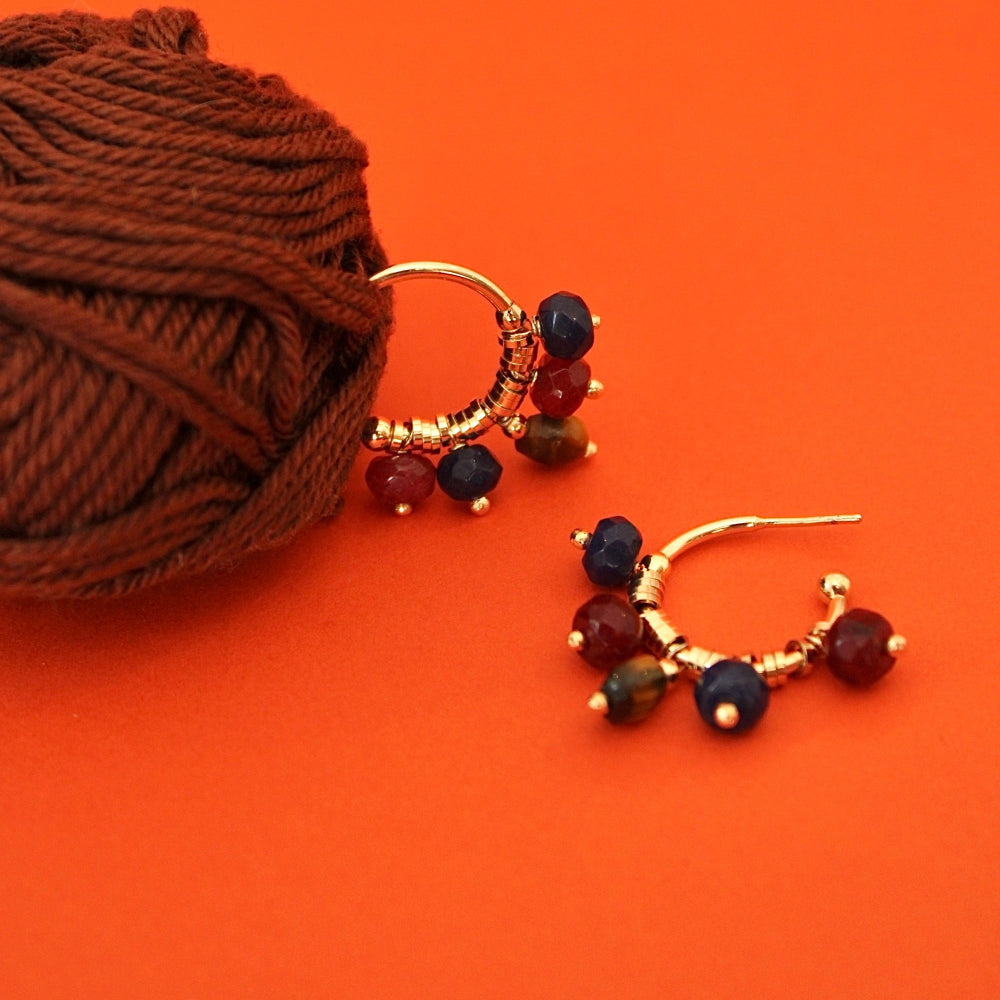 A pair of gold crescent-shaped dangle earrings with small multicolored jade natural stones.