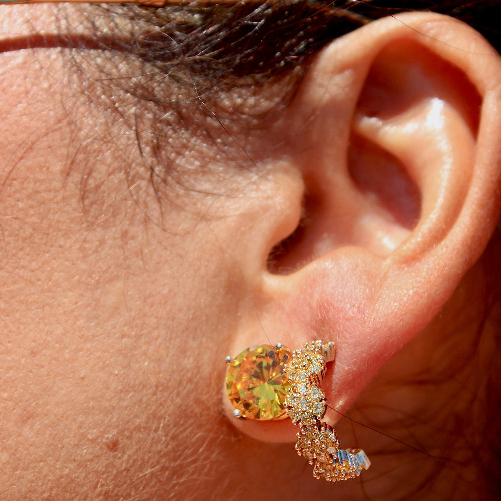 Close-up of an ear wearing a diamond earring with a multicolored gemstone.