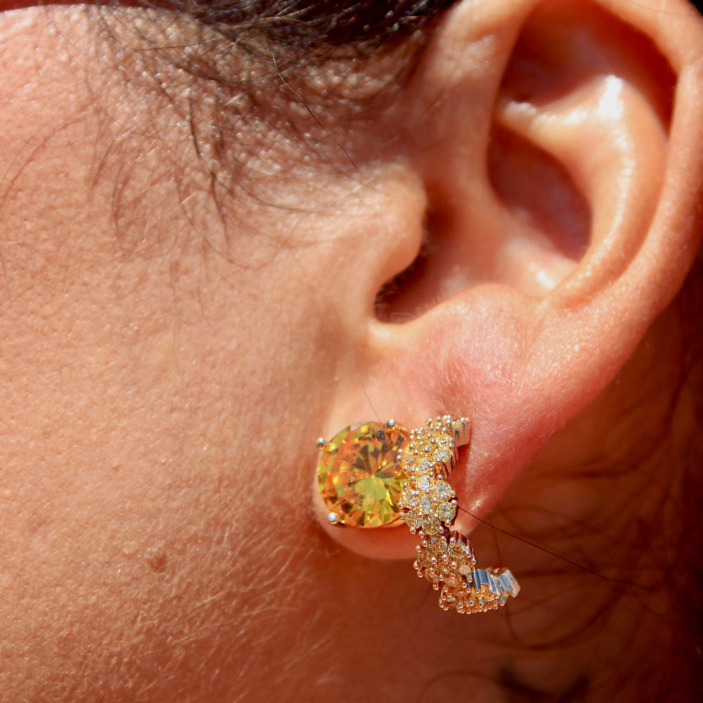Close-up of an ear wearing a diamond earring with a multicolored gemstone.