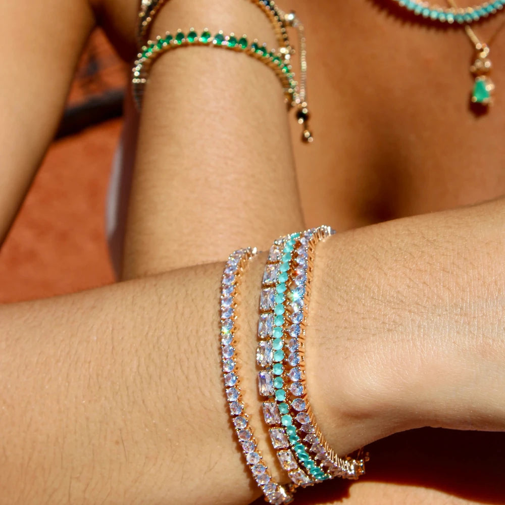 Close-up of a person's arm wearing multiple colorful bracelets on a blurred background