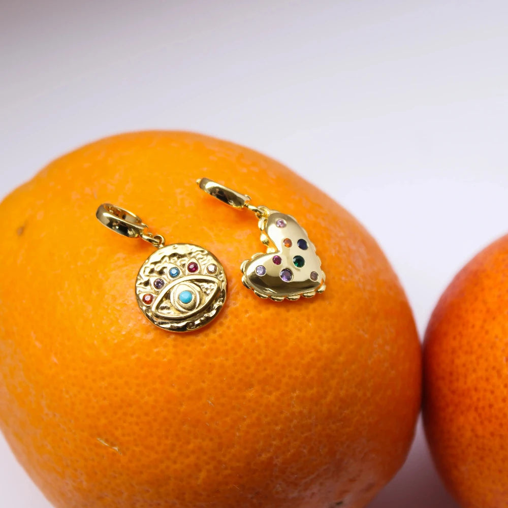 Gold earrings on an orange with a white background