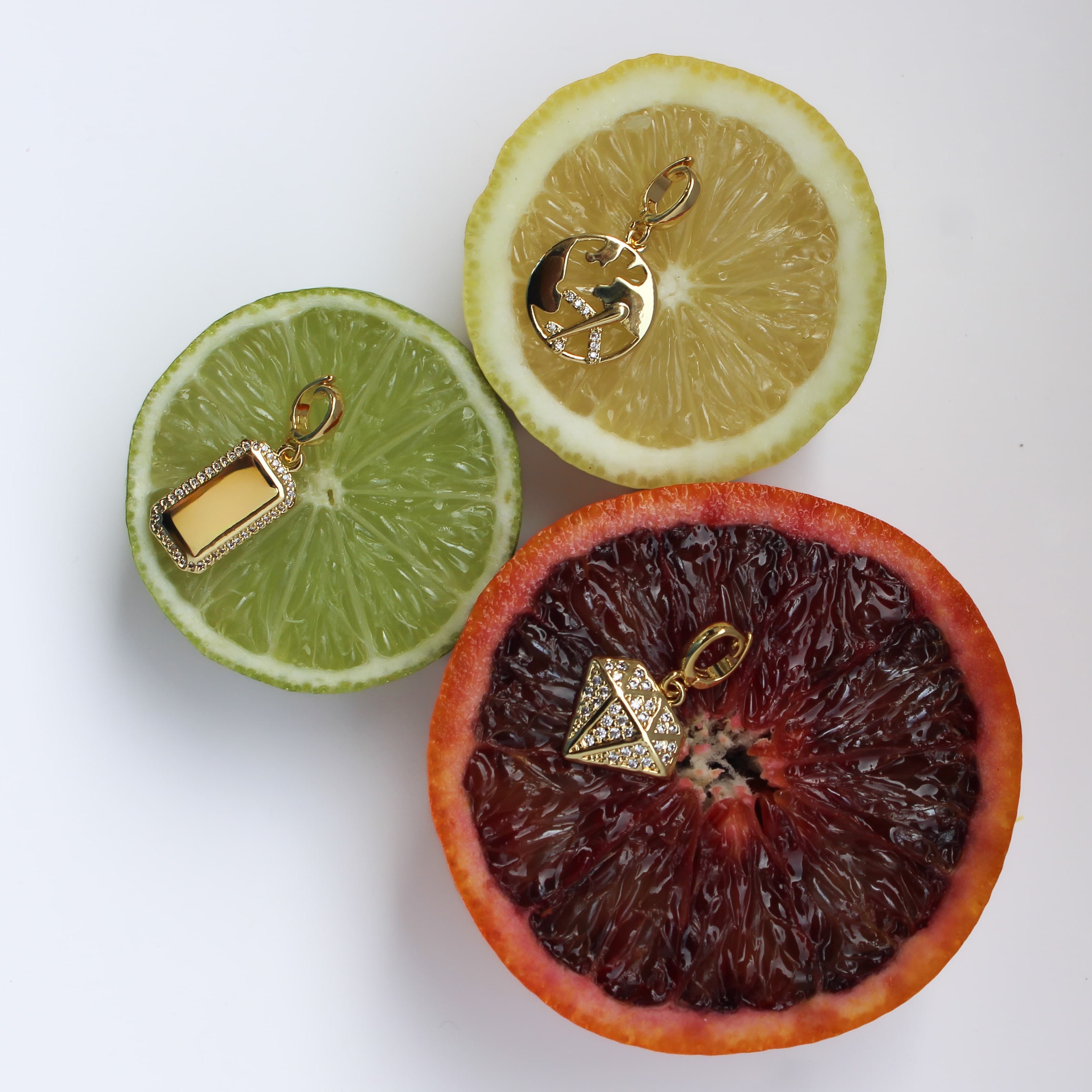 Gold jewelry charms on sliced citrus fruits on a white background
