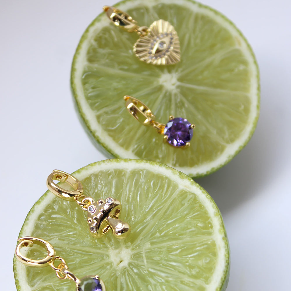 Gold earrings with purple stones on a sliced lime