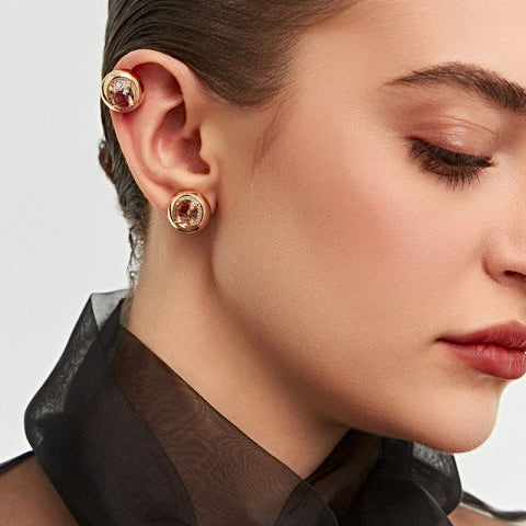 Close-up of a woman wearing gold earrings with a plain background