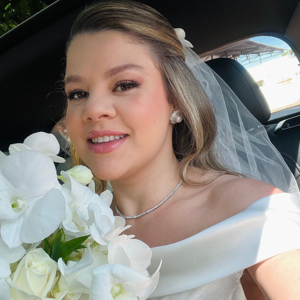 Woman in a wedding dress holding a bouquet of white flowers inside a car.