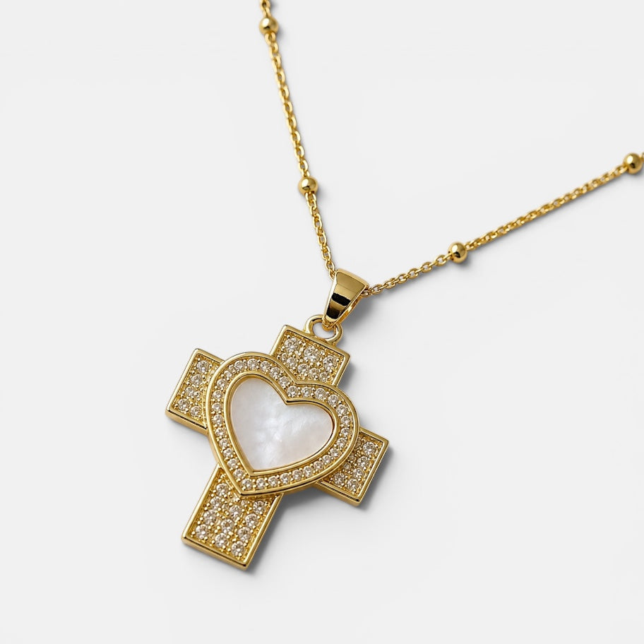 Gold cross necklace with heart design on a white background