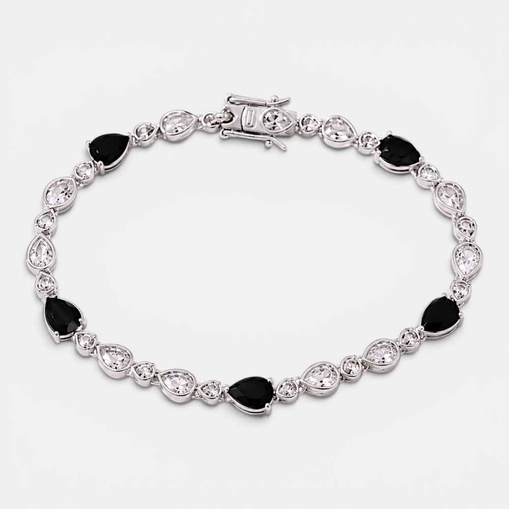 Silver bracelet with black and clear gemstones on a white background