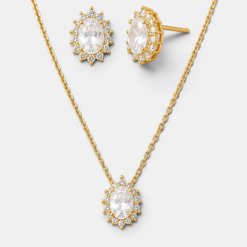 Gold jewelry set featuring a necklace and matching stud earrings with oval clear gemstones surrounded by small sparkling accents, shown on a light gray background.