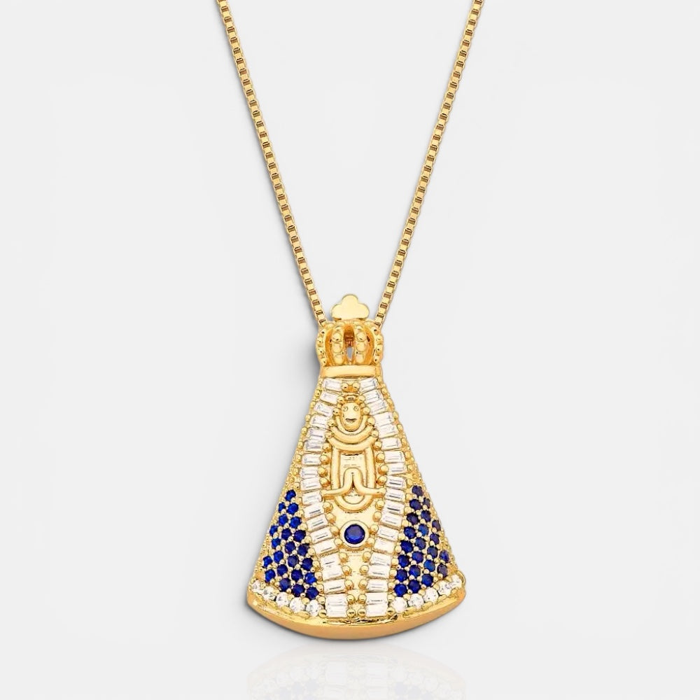 A gold pendant necklace featuring an Egyptian-style scarab beetle design, embellished with clear crystals and deep blue stones, shown on a light gray background.