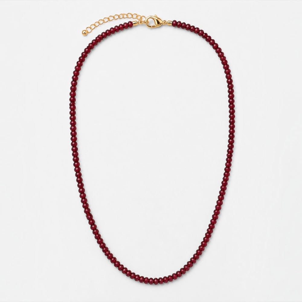 A beaded necklace made of small dark red beads with a gold clasp and extender chain, photographed on a clean light gray background.