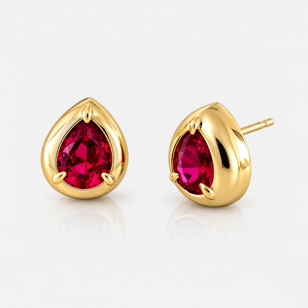 A pair of gold teardrop stud earrings with faceted deep pinkish-red gemstones, shown on a clean white background.