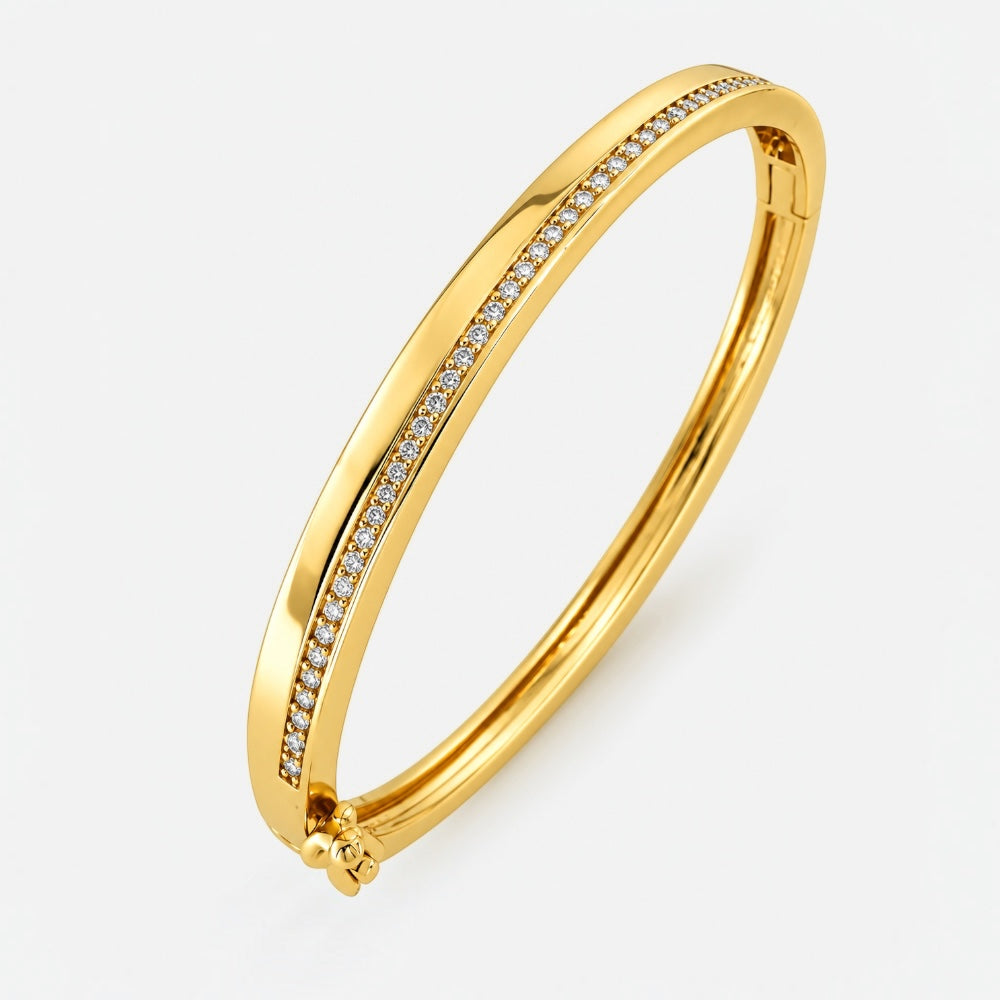A polished yellow gold hinged bangle bracelet featuring a channel-set row of small clear stones along one side, shown on a light gray background.