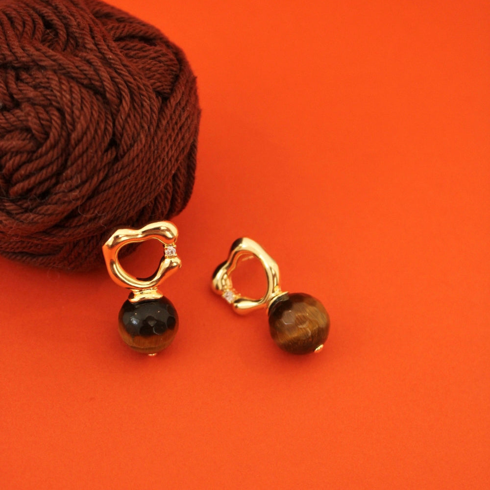 A pair of gold plated organic earrings with circular top and tiger eye natural stone
