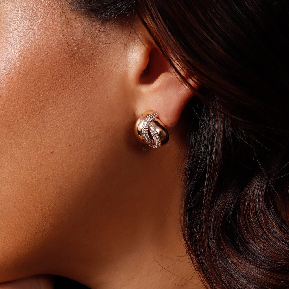 Close-up of a person wearing gold earrings with a dark background