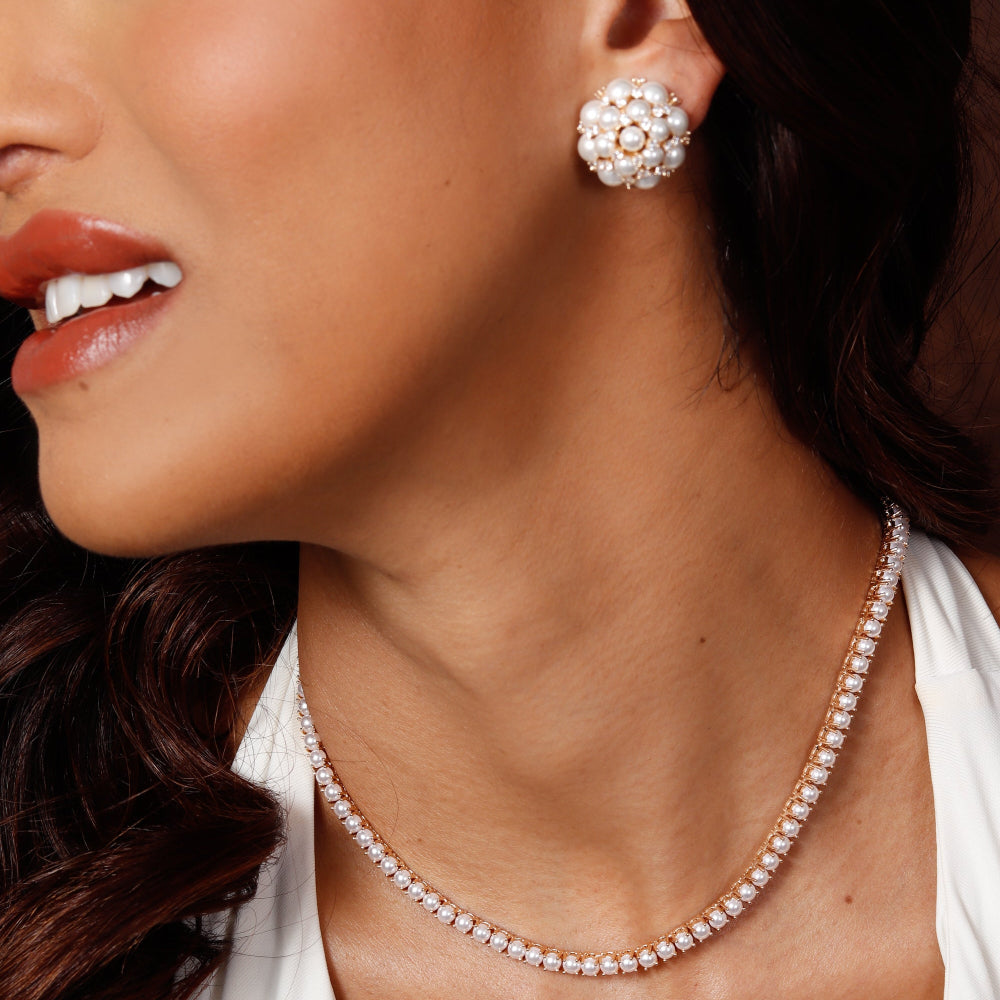 Close-up of a woman wearing pearl earrings and necklace with a blurred background