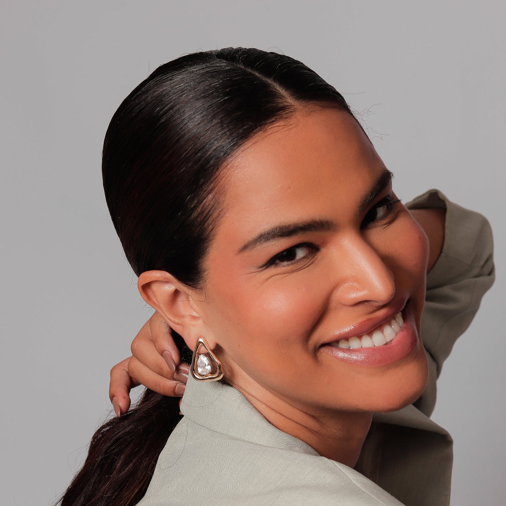 Woman with a ponytail wearing earrings against a gray background