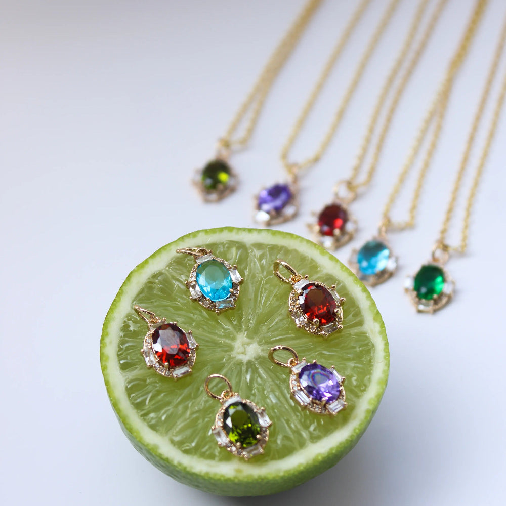 Gold necklaces with gemstone pendants on a sliced lime