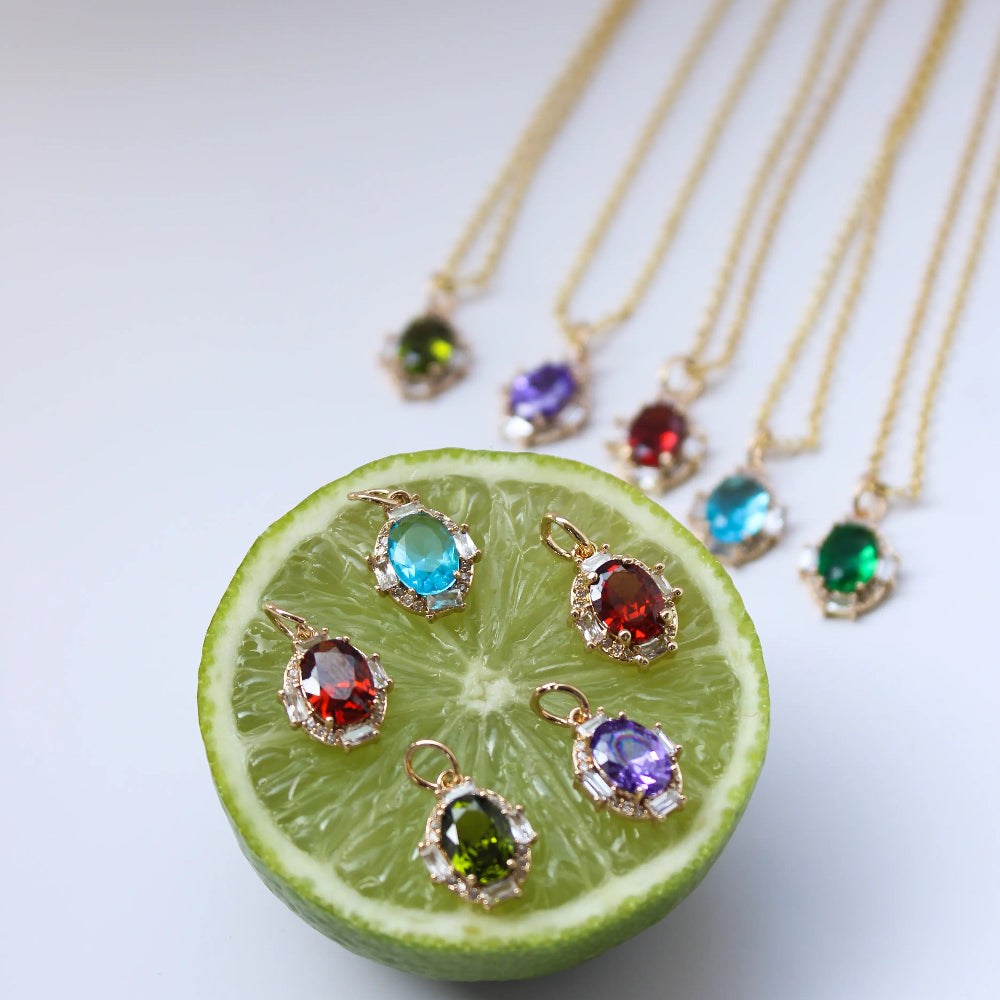 Gold necklaces with gemstone pendants on a sliced lime