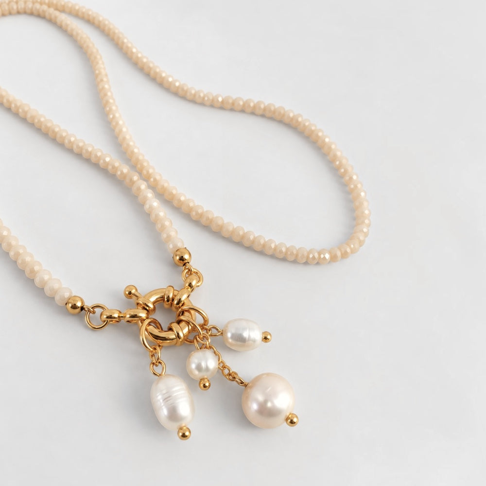 Angled view of cream faceted jade necklace and dangling freshwater pearl charms