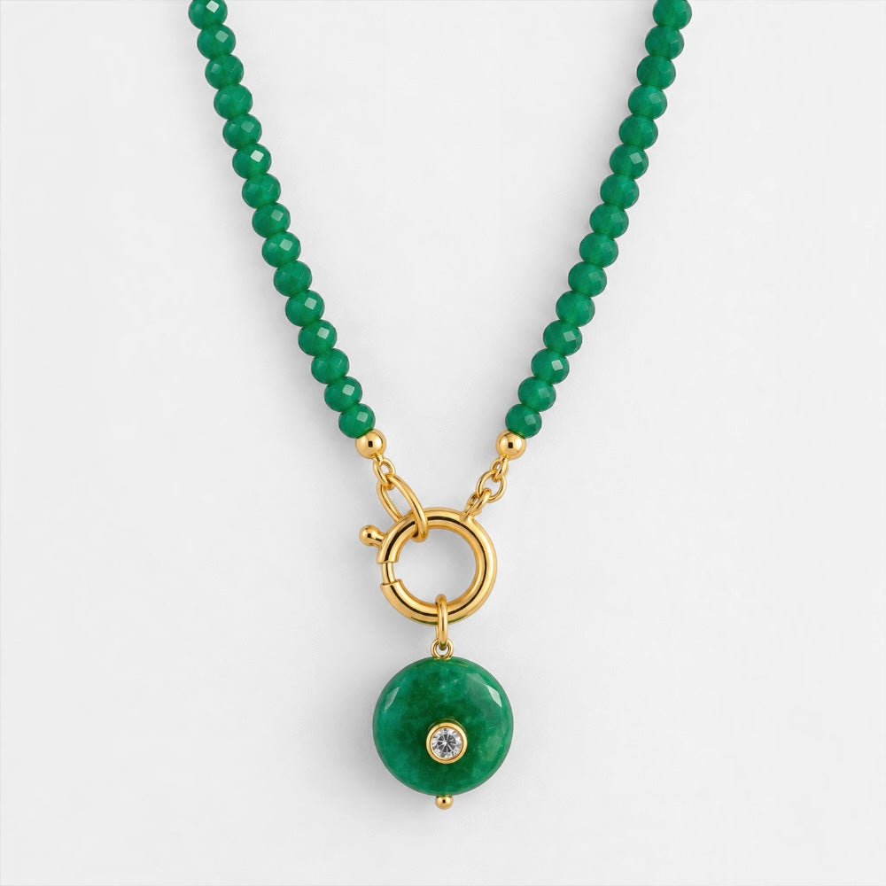 Close-up of faceted emerald-green jade beads and round green pendant with gold-plated details