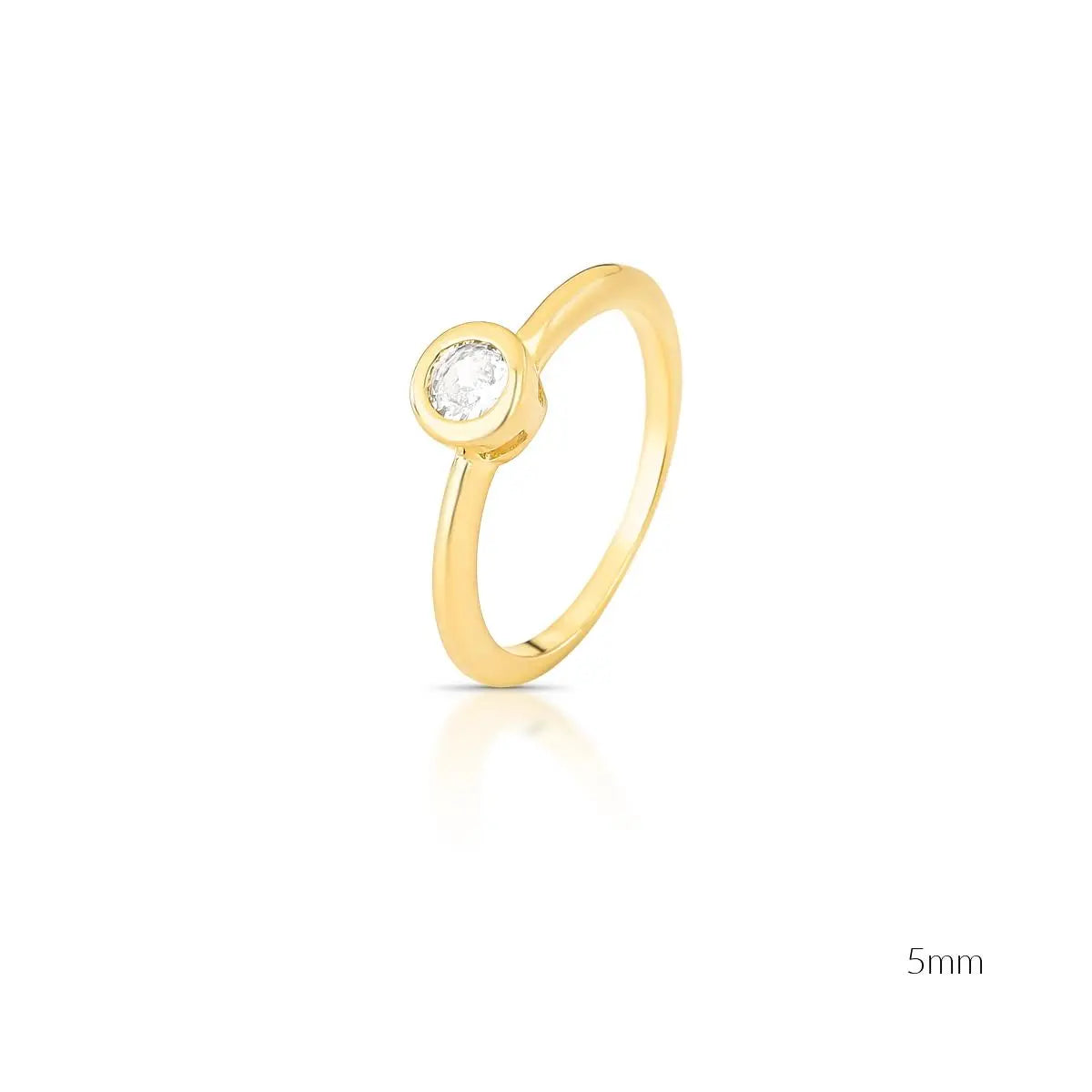 A gold solitaire ring with a single round-cut clear gemstone in a bezel setting, shown on a white background with a soft reflection and a '5mm' size indicator in the bottom right corner.