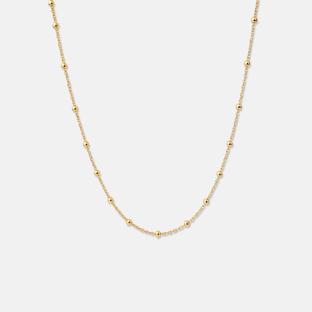Gold necklace on a light gray background