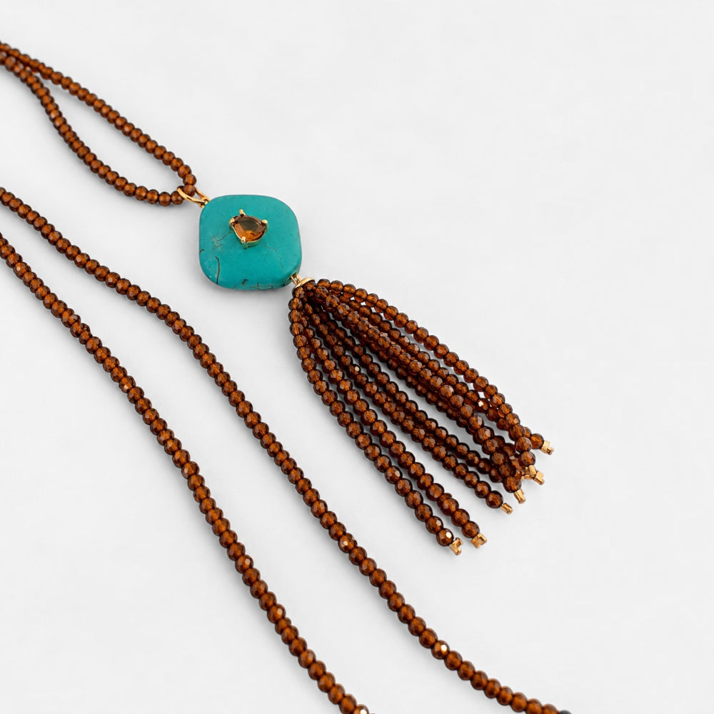 Side view of long brown jade beaded necklace with reconstituted turquoise square pendant and brown beaded tassel