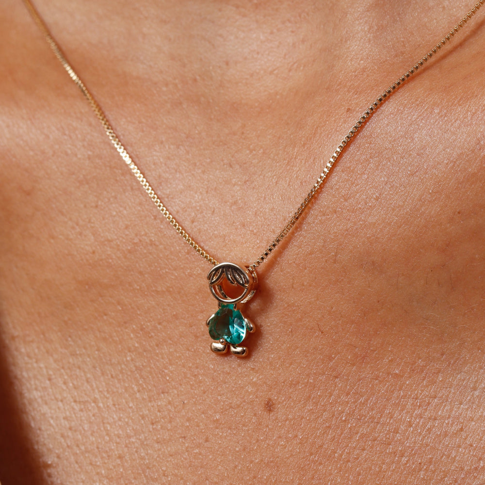 Gold necklace with a green gemstone pendant on a person's neck