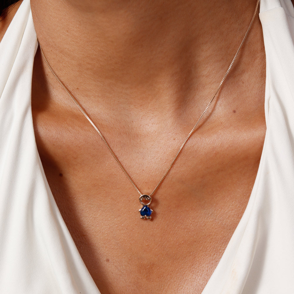 Necklace with a blue pendant worn by a person in a white top