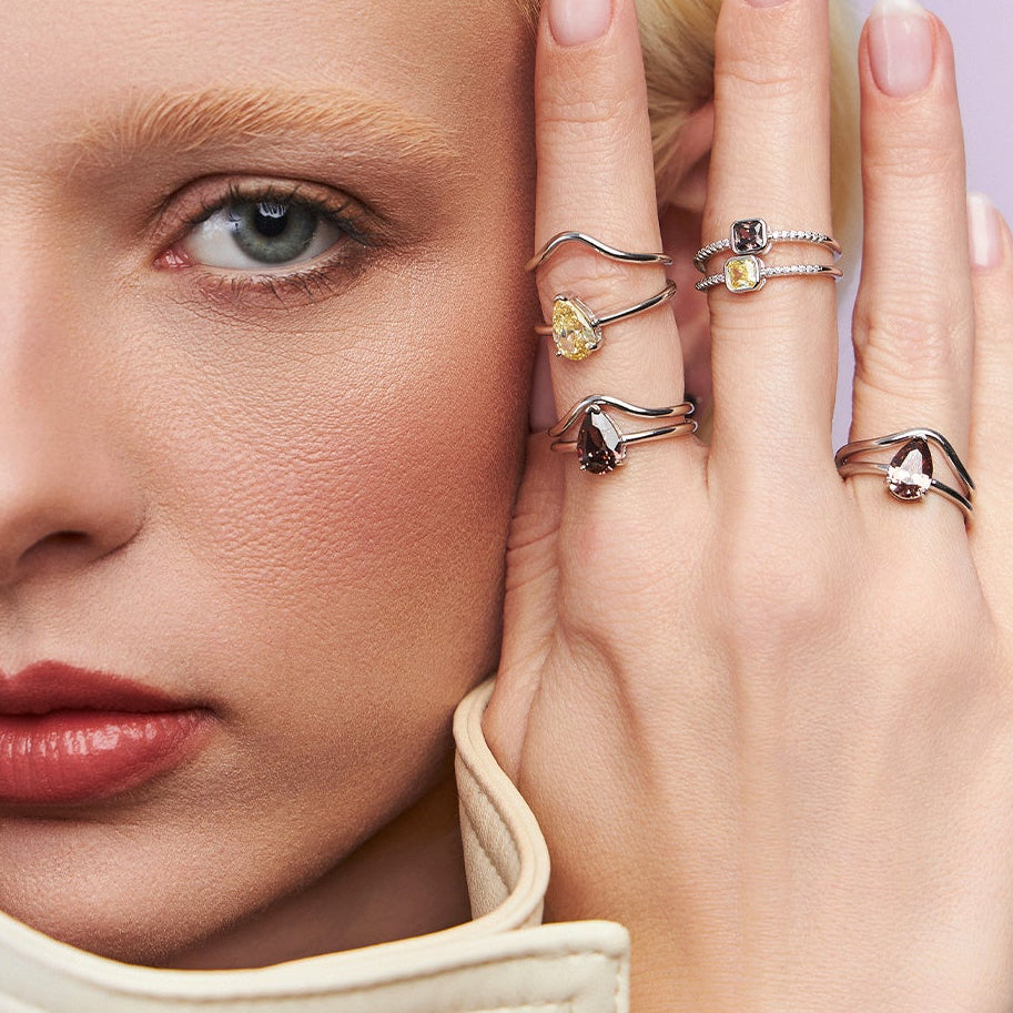 A close-up lifestyle shot of a blonde woman wearing multiple rings on her fingers, with the brand name 'LINHA PRATA' printed at the bottom.