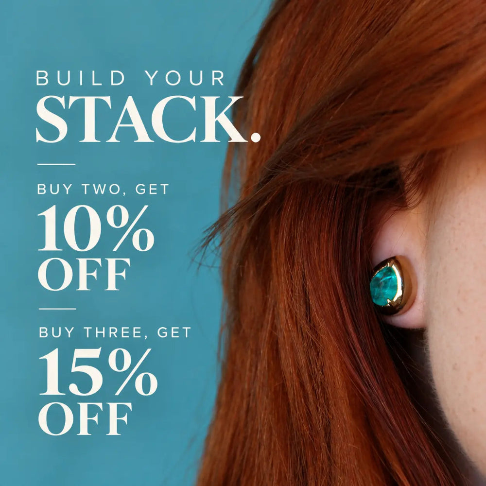 A close-up of a person's ear wearing a teardrop-shaped turquoise earring with a gold setting, next to promotional text that reads 'BUILD YOUR STACK. BUY TWO, GET 10% OFF BUY THREE, GET 15% OFF' on a teal background.
