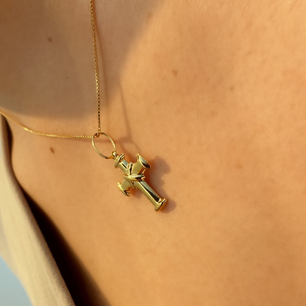 Gold necklace with a unique pendant on a person's neck