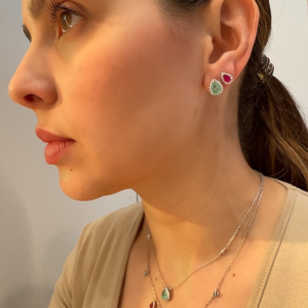 Close-up of a woman wearing a necklace and earrings with gemstones.