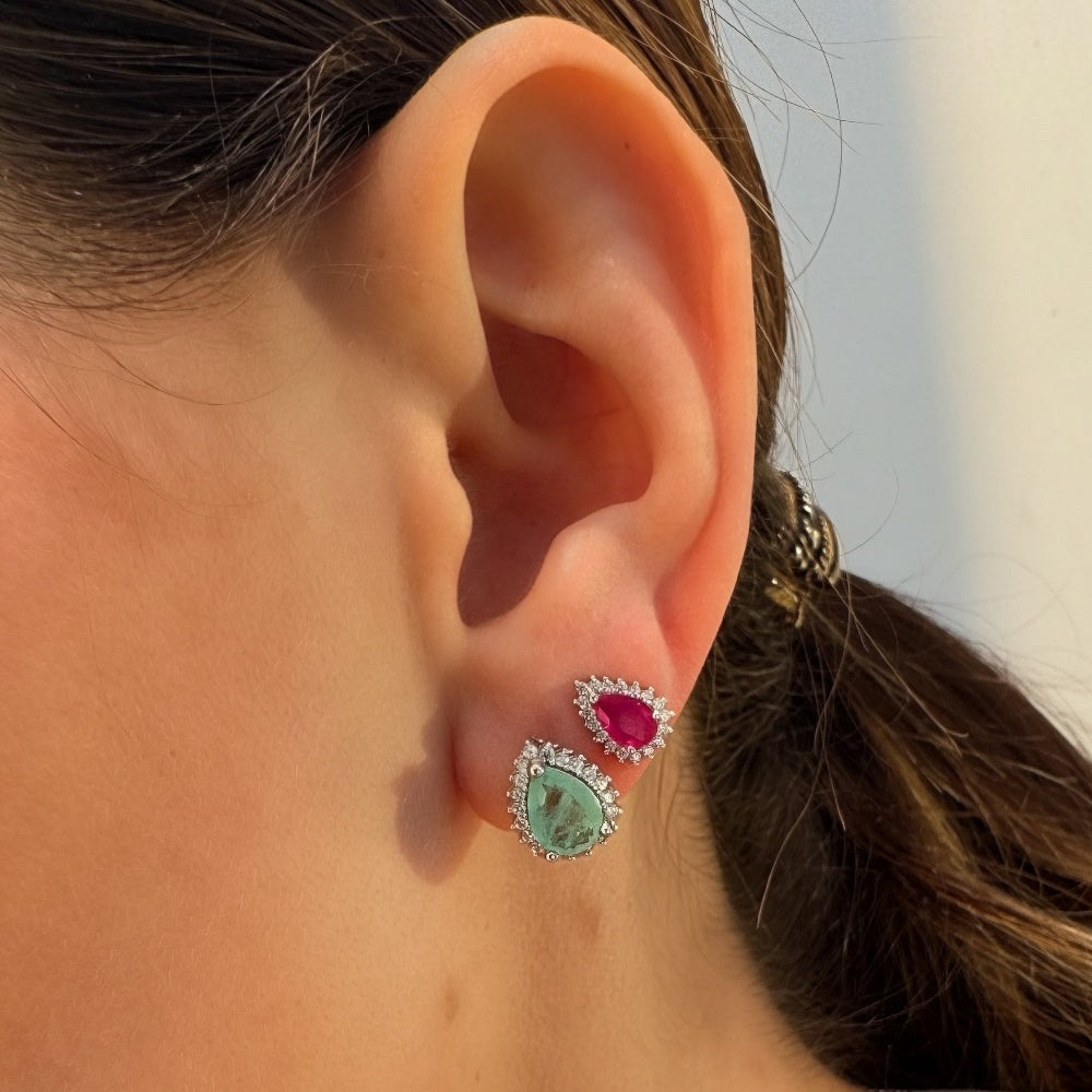 Close-up of an ear wearing two colorful earrings with a blurred background