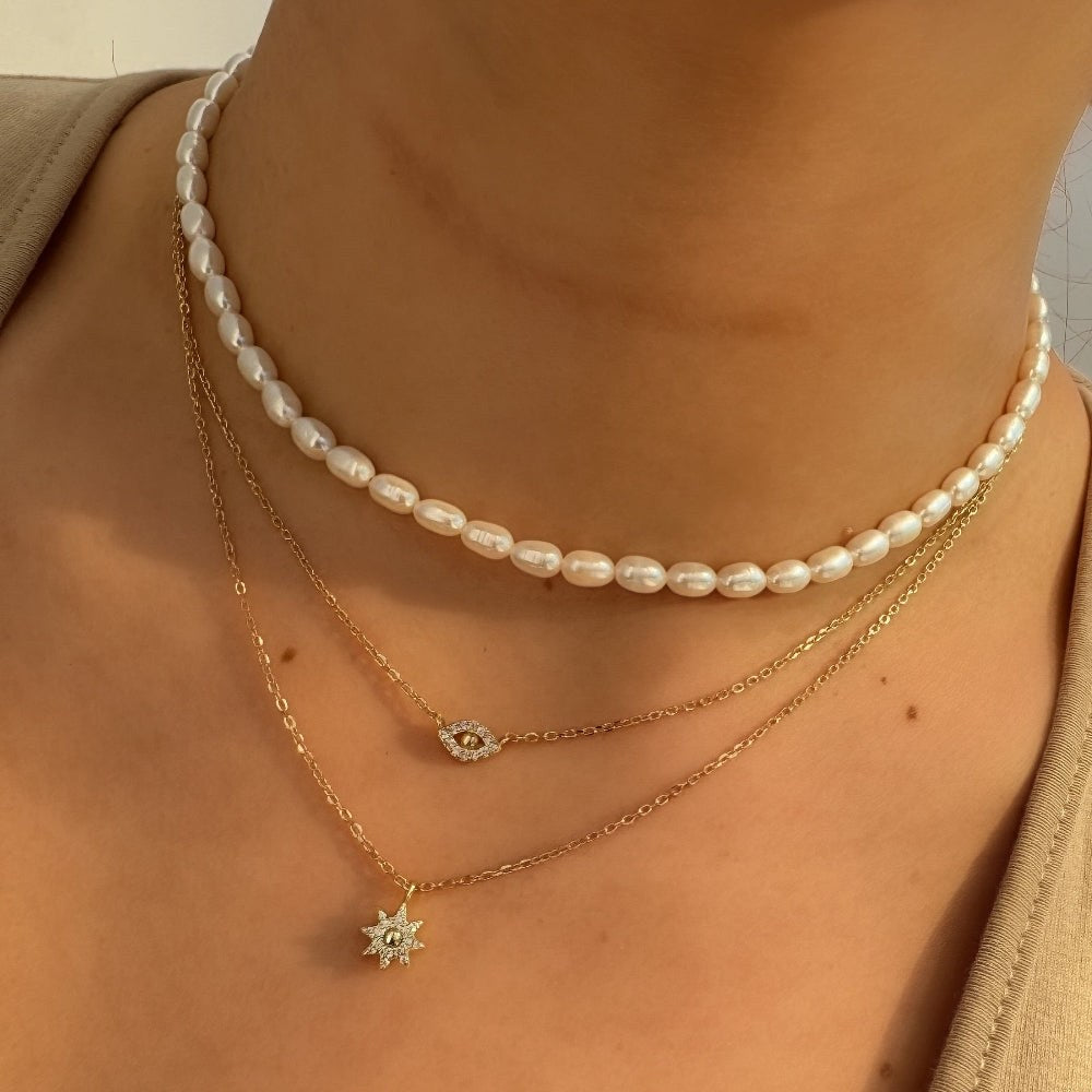 Close-up of a person wearing two necklaces with a blurred background